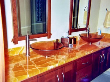 Широкая столешница из коричневого оникса в ванной комнате